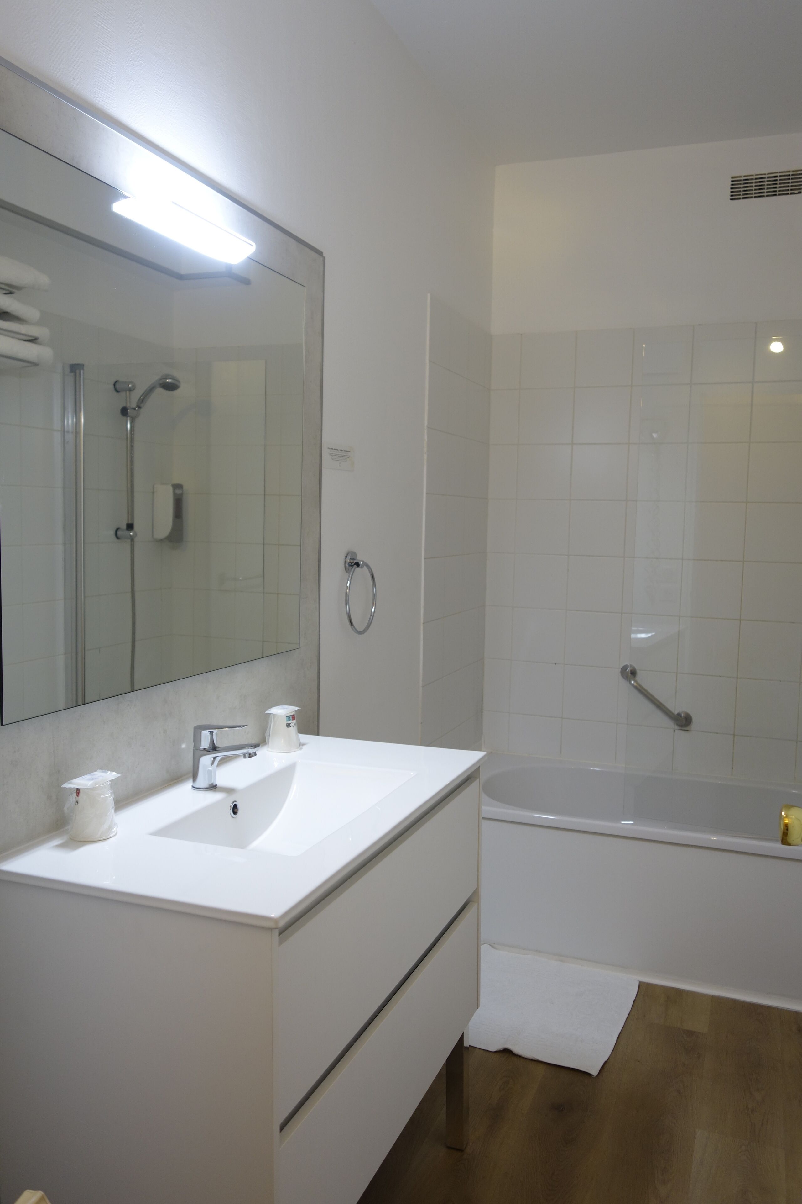 A modern bathroom with a white sink, mirror, and bathtub.