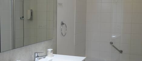 A modern bathroom with a white sink, mirror, and bathtub.