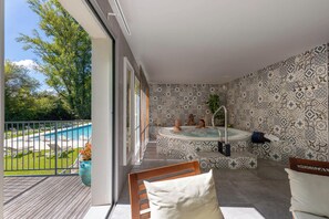 A balcony with a hot tub, a pool, and a view of the surrounding greenery. - Hôtel La Ségalière Spa Bar (Cajarc)