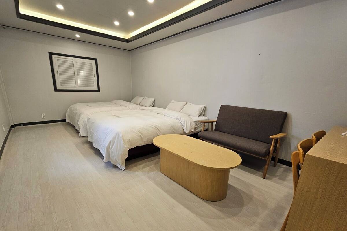 A modern bedroom with a bed, a sofa, and a wooden coffee table.