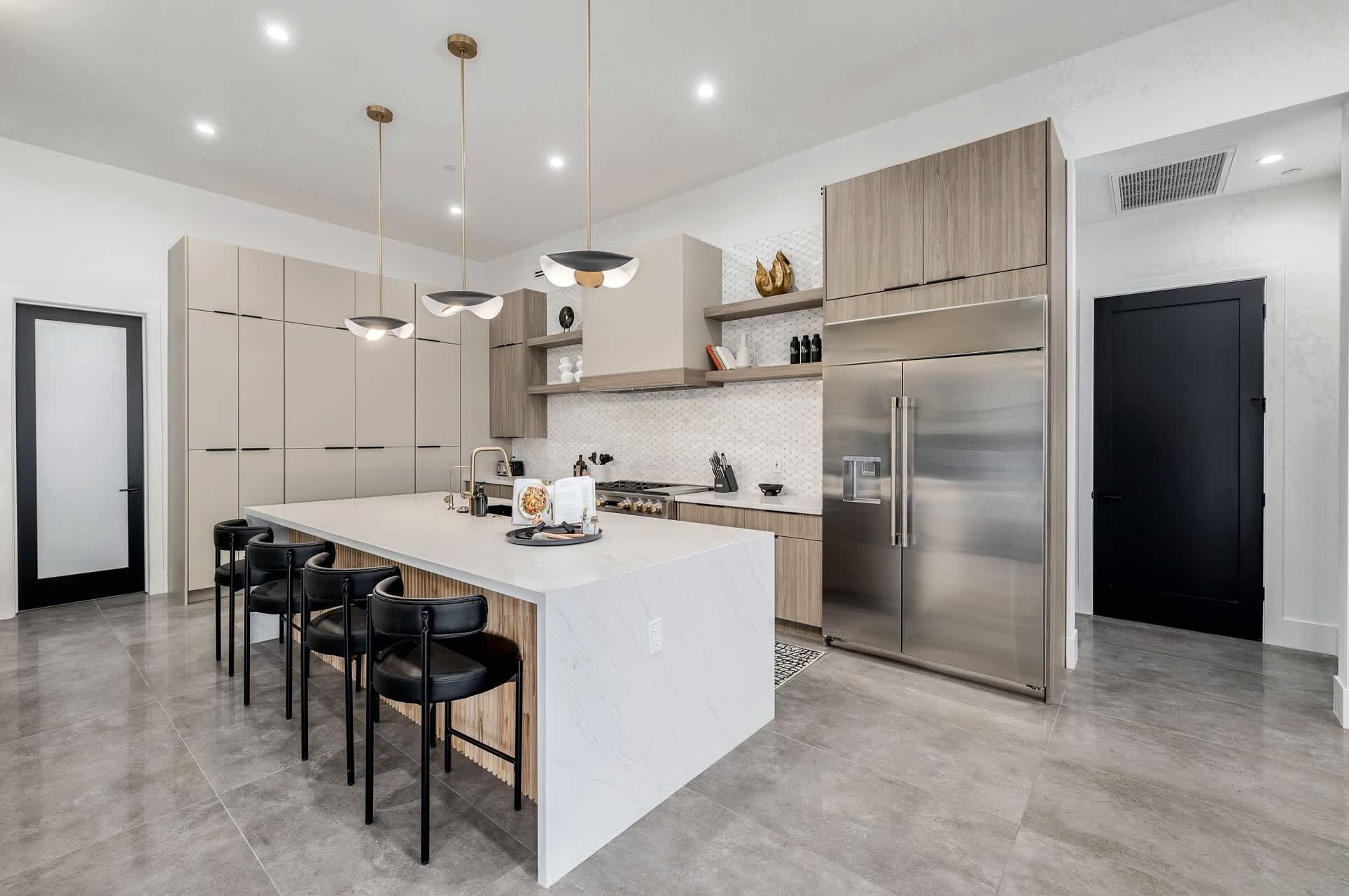 A modern kitchen with a central island, stainless steel appliances, and pendant lighting.