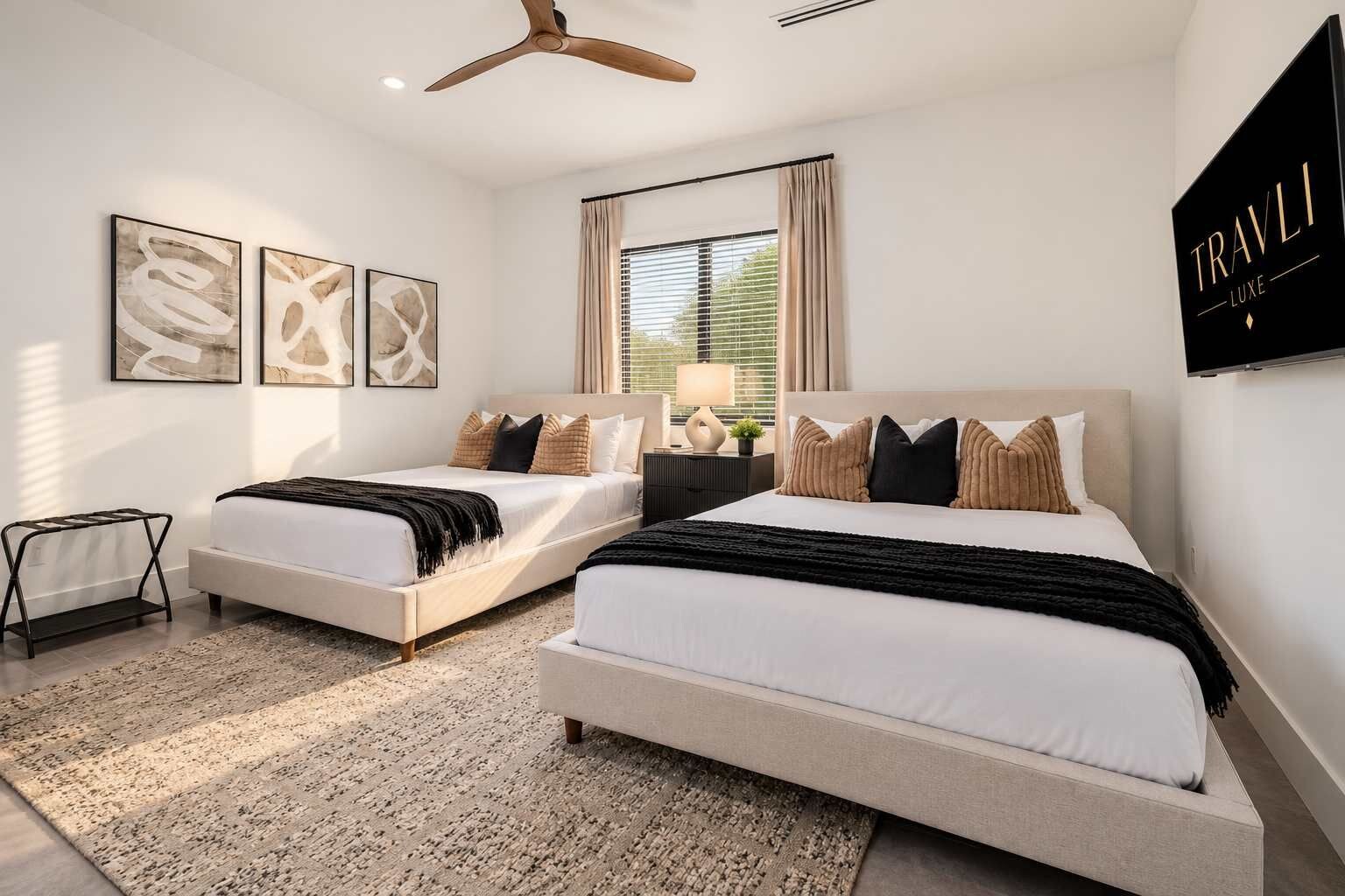 A modern bedroom with two beds, a ceiling fan, and artwork on the walls.