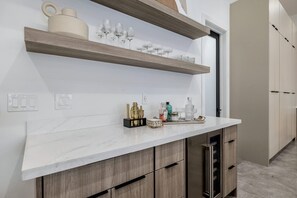 Una cocina moderna con encimeras de mármol, armarios de madera y estantes abiertos con cristalería.