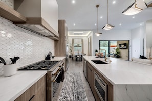 Una cocina moderna con una isla central, electrodomésticos de acero inoxidable e iluminación colgante.