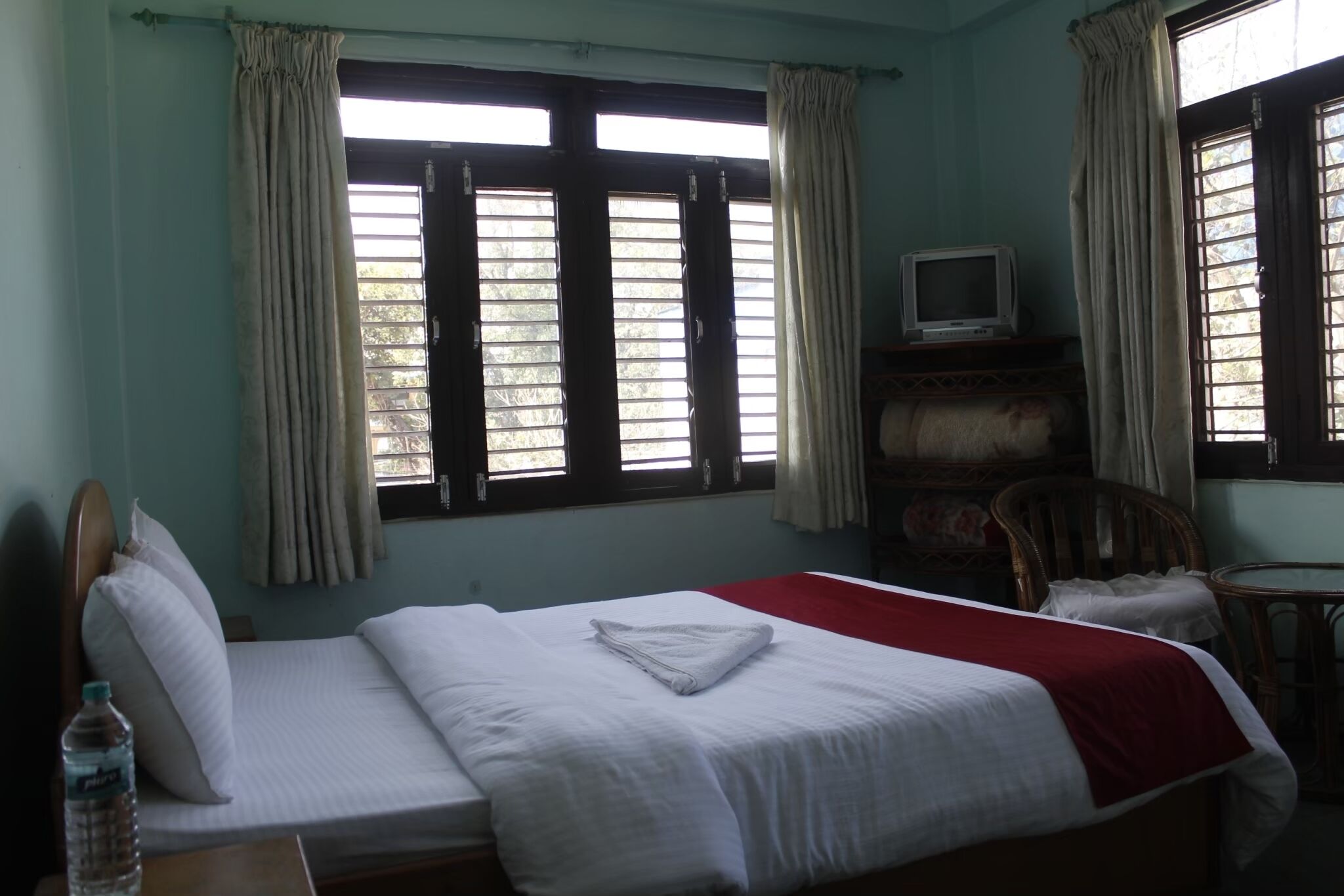 A hotel room with a bed, a television, a chair, and a table.