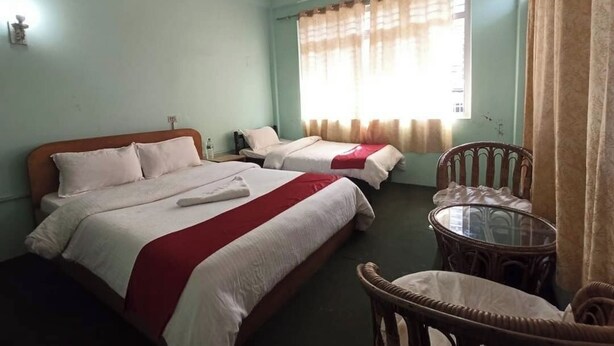 Une chambre d’hôtel avec deux lits, une petite table et une chaise.
