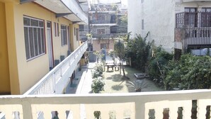 Une cour avec un bâtiment jaune, un bâtiment blanc et un balcon doté de balustrades.