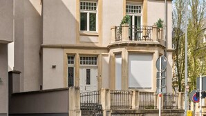 A two-story building with a gabled roof, a central chimney, and a balcony with railings. - Spacious & Tranquil Room in Limpertsberg (Luxembourg)