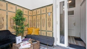 A reception area with a sofa, a coffee table with magazines, a potted plant, and a wall with decorative tiles. - Spacious & Tranquil Room in Limpertsberg (Luxembourg)