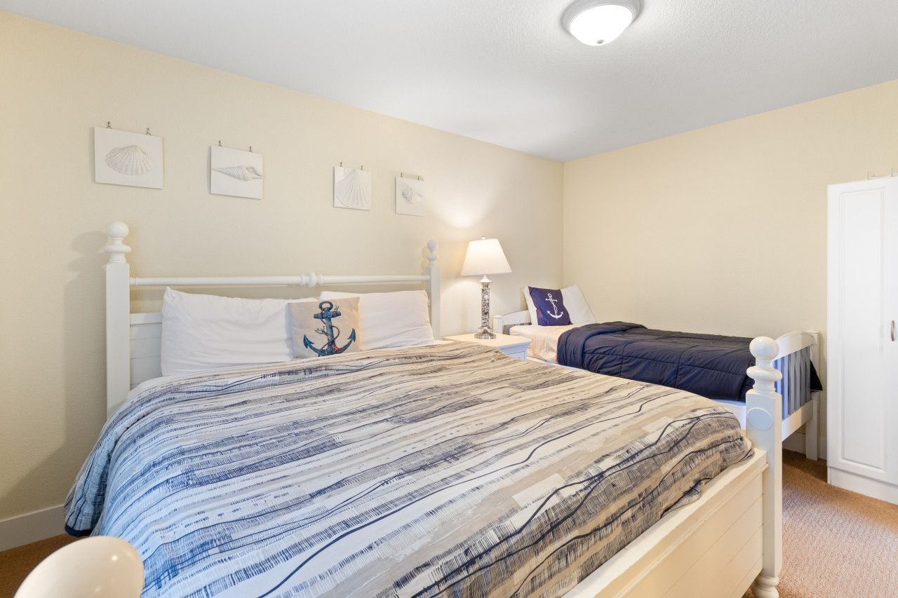 A bedroom with two beds, a nightstand with a lamp, and wall-mounted artwork.