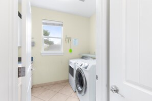 Une buanderie équipée d’un lave-linge, d’un sèche-linge, d’une fenêtre et d’une porte.