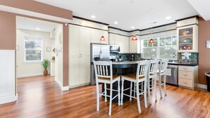 Une cuisine moderne avec des meubles blancs, un plan de travail noir et un coin repas avec des chaises blanches.