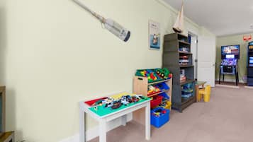 Een kinderspeelruimte met een tafel, planken en speelgoed.