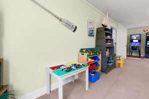 Un espace de jeux pour enfants avec une table, des étagères et des jouets.