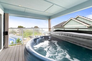 Ein Whirlpool auf einer Holzterrasse mit freiem Blick auf die Umgebung.