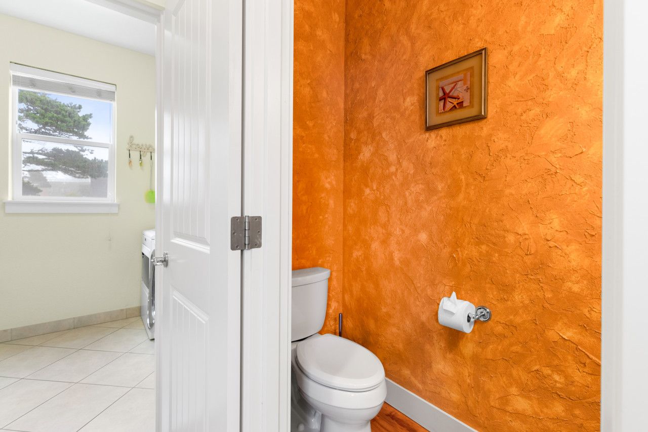 A bathroom with a white toilet, a white door, and an orange textured wall.