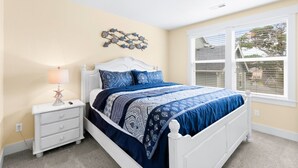 A bedroom with a white bed, blue bedding, a starfish lamp, and a wall decoration.