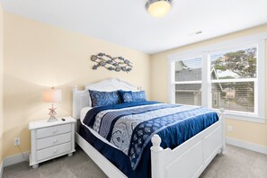 Ein Schlafzimmer mit einem weißen Bett, blauer Bettwäsche, einer Lampe in Form eines Seesterns und einer Wanddekoration.