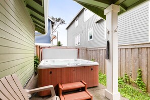 Ein Garten mit Whirlpool, Holzterrasse und zwei Stühlen.