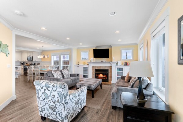 A spacious living room with a fireplace, a dining area, and a kitchen. - Green Turtle · Ocean View, Hot Tub, Sleeps 10 (Lincoln City)