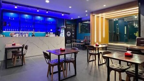 Un restaurant moderne doté d’un bar, de différents types de tables et offrant une vue sur la rue.
