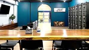 Un espace de bureau moderne avec un comptoir d’accueil en bois, des chaises noires, une grande fenêtre et une rangée de classeurs.