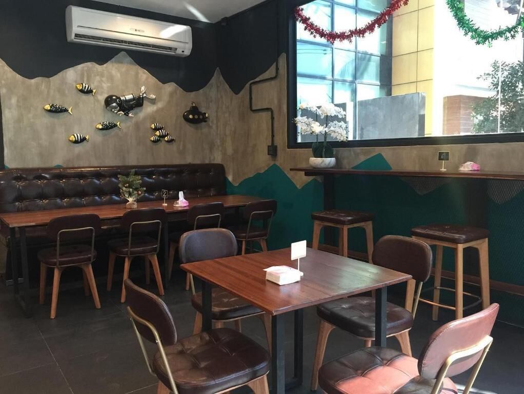 A restaurant interior with a wooden table and chairs, a cushioned bench, and decorative wall art.
