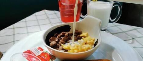 Piattino per la colazione con pane tostato, cereali e latte che viene versato.