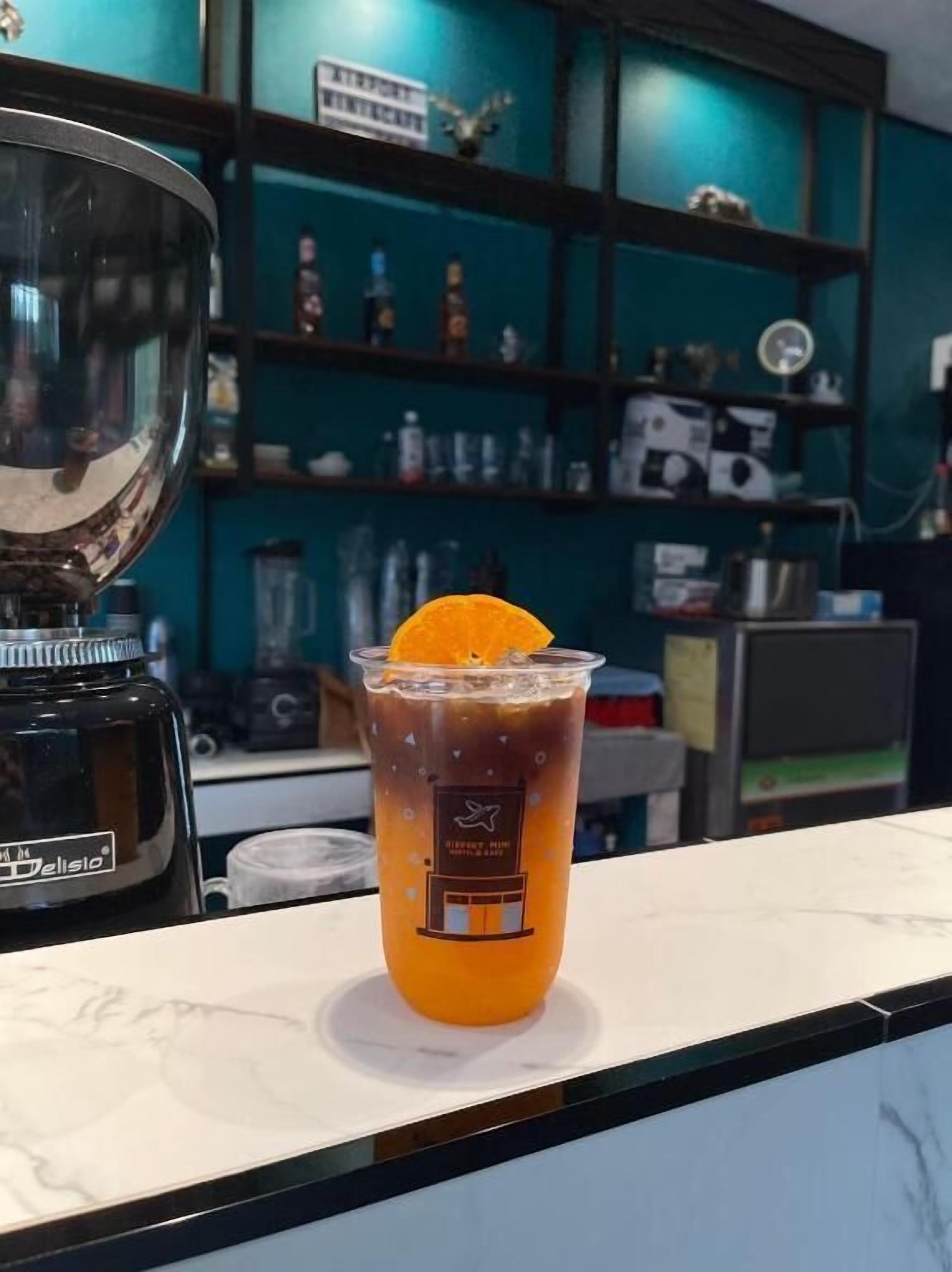 Une boisson servie dans un verre transparent, avec une tranche d’orange posée sur un comptoir.
