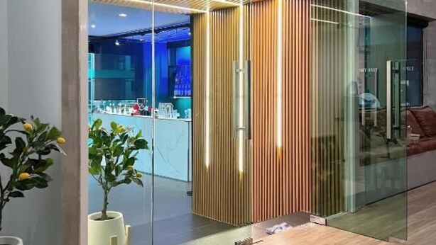 A modern interior with a glass partition, wooden slats, and a visible kitchenette area. - Airport Mini Hostel at Don Muang Airport (Bangkok)