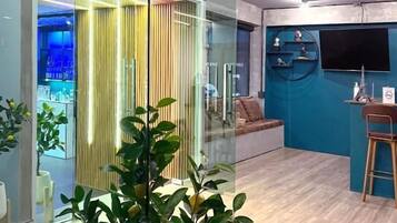 A modern interior with a glass partition, a seating area, and a small bar counter.