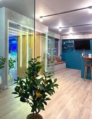 Een modern interieur met een glazen scheidingswand, een zithoek en een klein barretje.
