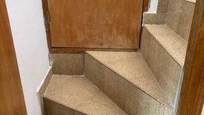 Una escalera con peldaños alfombrados en tono beige que conducen a una puerta de madera.