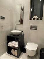 Casa de banho moderna com uma pia branca, toucador preto e sanita branca.