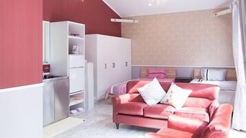 A modern bedroom with a red wall, a white wardrobe, a pink sofa, and a bed with a white headboard.