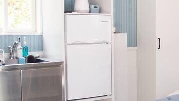 Una cocina compacta con un refrigerador blanco, un lavamanos y una ventana con cortinas.