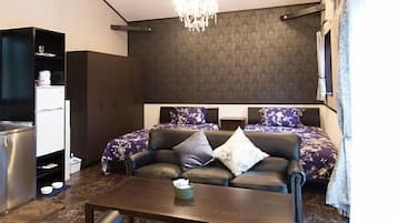 Una sala de estar moderna con un conjunto de sofá, una mesa de centro y una cocina integrada con nevera y armarios.