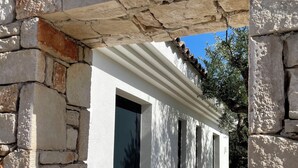 Un arco de piedra que da paso a un edificio de fachada blanca y entrada con azulejos.