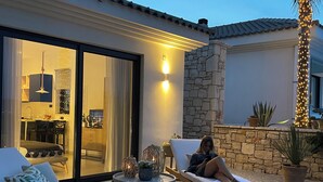 Un patio con dos sillones de descanso, una mesa y una mujer relajándose.