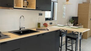 Una cocina moderna con un lavamanos negro, armarios de madera y una ventana.