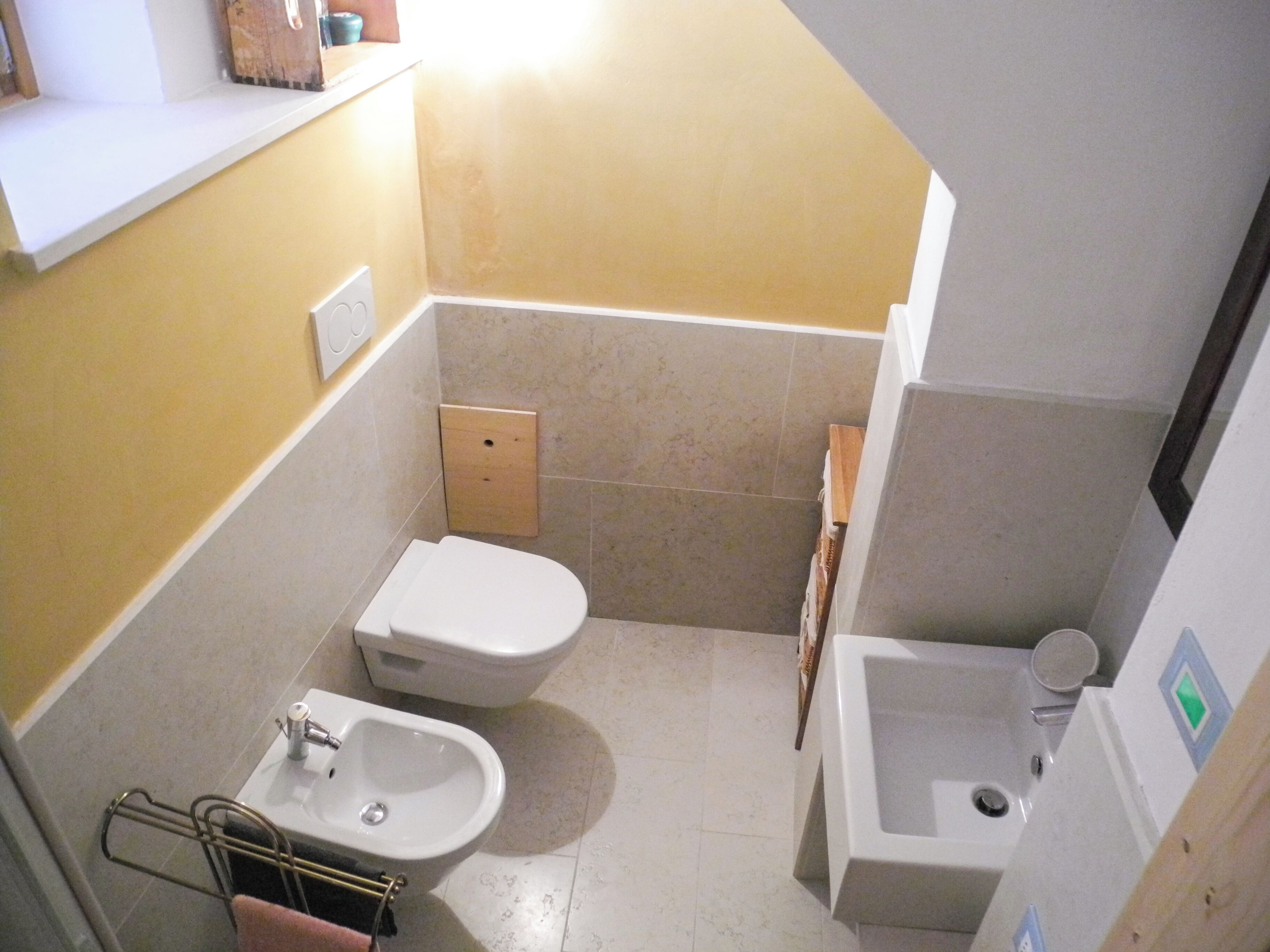 A compact bathroom with a toilet, bidet, and sink.