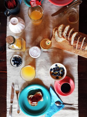 A breakfast setting with toast, blueberries, honey, and a variety of beverages on a table. - CasaZefira (Feltre)