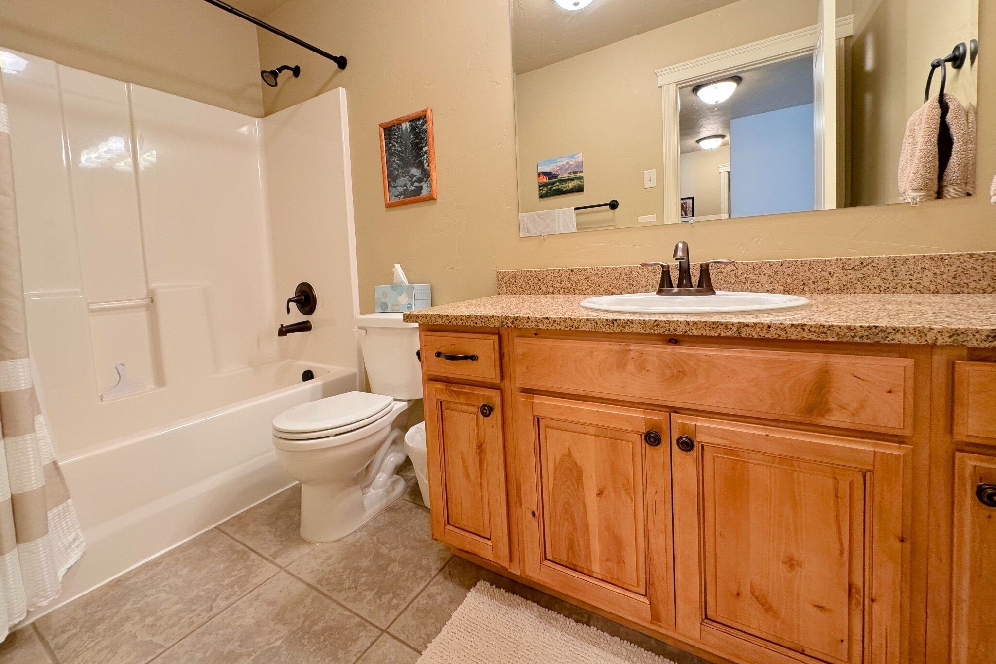 Un baño con bañera, inodoro, tocador de madera y espejo.