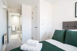 Quarto de hotel com cama, banheiro e porta para outro cômodo.
