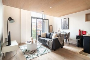 Un salon moderne avec un canapé, une table basse et un téléviseur. Il y a également un coin repas avec des chaises et une table.
