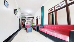 Un vestíbulo de hotel con un sofá rojo, un mostrador de recepción y un suelo de baldosas.