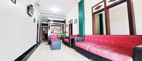 A hotel lobby with a red sofa, a reception desk, and a tiled floor.