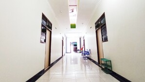 Un pasillo largo y estrecho con paredes blancas y detalles en negro, que conduce a una puerta al final.