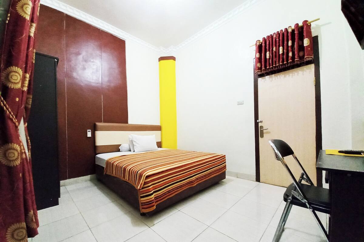 A hotel room with a bed, a desk, a chair, and a wardrobe.