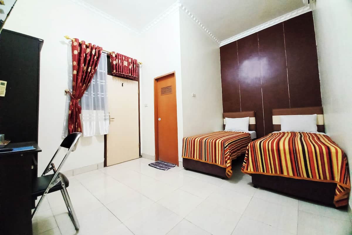 A hotel room with two beds, a desk, and a chair.